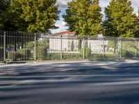 a street that has a fence and a truck behind it in front of a building