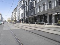 a narrow city street is on the right side of buildings with two trolley cars parked on the tracks