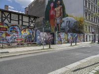 an empty city street has a wall with a mural on it next to a street