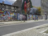 an empty city street has a wall with a mural on it next to a street