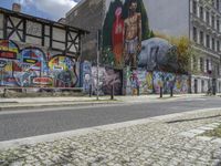 an empty city street has a wall with a mural on it next to a street