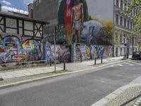 an empty city street has a wall with a mural on it next to a street