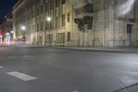 an empty street is lit up at night with red lights reflecting in the dark windows