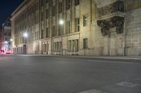 an empty street is lit up at night with red lights reflecting in the dark windows