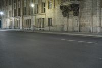 an empty street is lit up at night with red lights reflecting in the dark windows