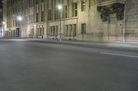 an empty street is lit up at night with red lights reflecting in the dark windows