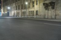 an empty street is lit up at night with red lights reflecting in the dark windows