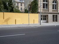a city street and an old building are empty in this image, while the building has been painted yellow with white trim