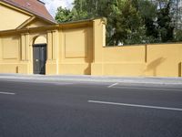 a city street and an old building are empty in this image, while the building has been painted yellow with white trim