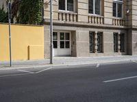 a city street and an old building are empty in this image, while the building has been painted yellow with white trim