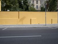 a city street and an old building are empty in this image, while the building has been painted yellow with white trim