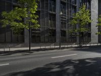 a city street with trees in front of some tall buildings and an orange traffic light