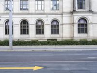 an arrow sign on a sidewalk in front of a building on a street corner and a yellow arrow pointing toward it