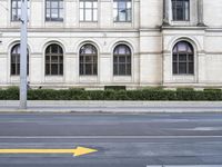 an arrow sign on a sidewalk in front of a building on a street corner and a yellow arrow pointing toward it