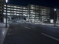 a empty street in an empty building at night time with streetlights around it and cars parked outside