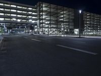 a empty street in an empty building at night time with streetlights around it and cars parked outside