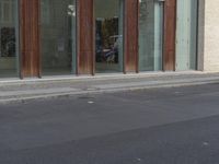 a person riding a skateboard on the sidewalk near a building with windows and a sign reading no standing here