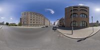 a wide angle view of a street with several buildings and some people driving in a car