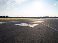 a small plane is parked in a runway at an airport with the sun behind it