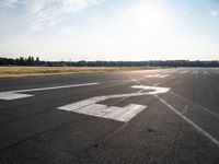 a small plane is parked in a runway at an airport with the sun behind it