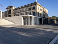 the large, empty sidewalk with multiple columns in front of the building with two signs