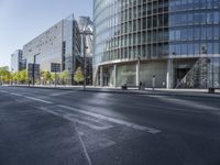 the empty streets are lined with tall buildings with glass walls on each side and people walking in the distance