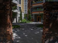 a residential driveway with a bench and bushes in between buildings and green grass on either side