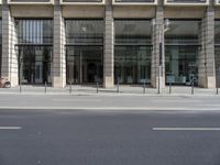 a street view of a large glass store building with lots of windows and a man riding a bicycle