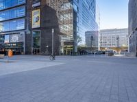 people ride their bikes through the city intersection in front of a building with many large windows