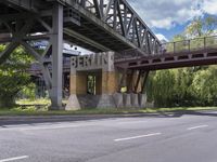 a street with an overpass crossing over water from a train bridge across the street