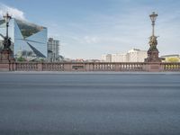 an empty city street next to a bridge and a tall building with tall buildings behind it