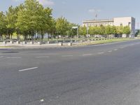 an empty street in front of a building and trees in the middle of the road