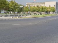 an empty street in front of a building and trees in the middle of the road