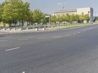 an empty street in front of a building and trees in the middle of the road