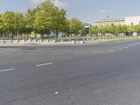 an empty street in front of a building and trees in the middle of the road