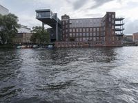 large body of water next to a building near the river with people on it and boats in the water