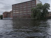 large body of water next to a building near the river with people on it and boats in the water