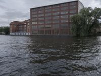 large body of water next to a building near the river with people on it and boats in the water