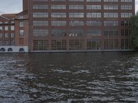 large body of water next to a building near the river with people on it and boats in the water