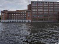 large body of water next to a building near the river with people on it and boats in the water