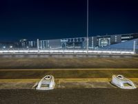 four white boats sit on a curb in the middle of a parking lot by a stadium
