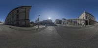 a 360 - view shows the sun through the sky above buildings on a street corner