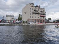 large body of water next to a building near the river with people on it and boats in the water
