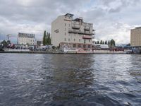 large body of water next to a building near the river with people on it and boats in the water
