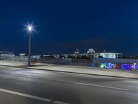 large building on the street with lights in front and other buildings nearby at night with no one moving