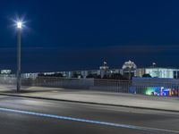 large building on the street with lights in front and other buildings nearby at night with no one moving