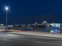 large building on the street with lights in front and other buildings nearby at night with no one moving