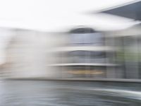 a blurry picture of a building from the water in a river area with one yellow umbrella