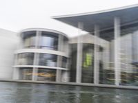 a blurry picture of a building from the water in a river area with one yellow umbrella