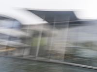 a blurry picture of a building from the water in a river area with one yellow umbrella